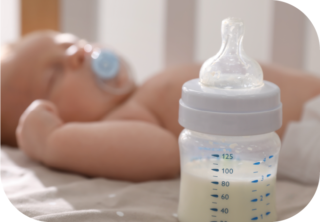 Un bebé recién nacido come la fórmula de un biberón por sí mismo sin la  ayuda de las manos. Un niño bebe la mezcla de leche de una botella tumbada  en la